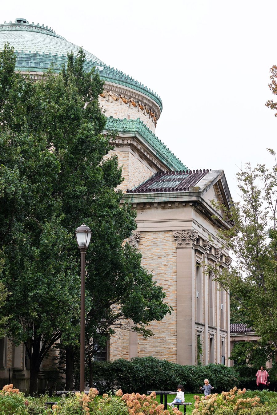 The library in 2018 from the side, its dome above full-grown trees and a street lamp.