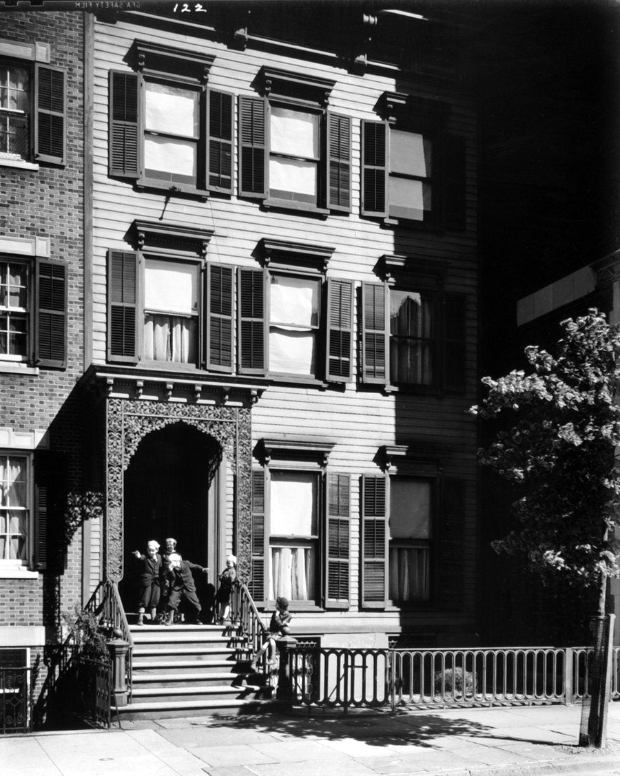 A clapboard house on Willow Street in 1936, its iron-railed stoop, people sitting on the steps.