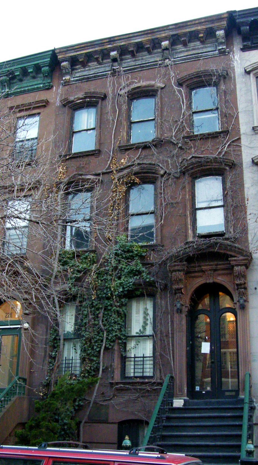 The brownstone at 20 East 127th Street in 2009, ivy on its front, a stoop up to the door.