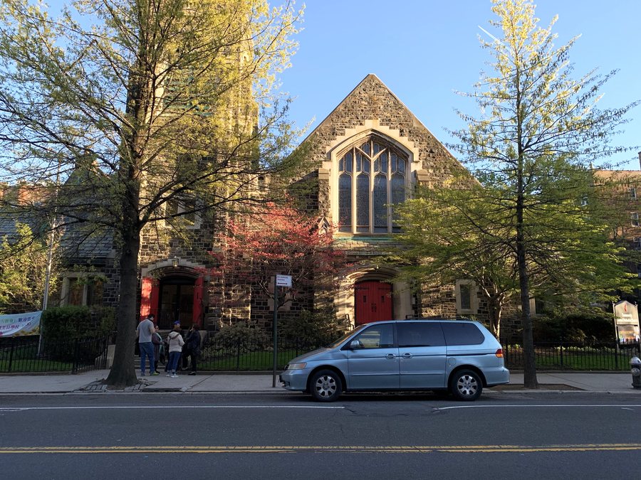 Community United Methodist Church in Jackson Heights in 2019: a stone church with a tall pointed window, trees in bud.