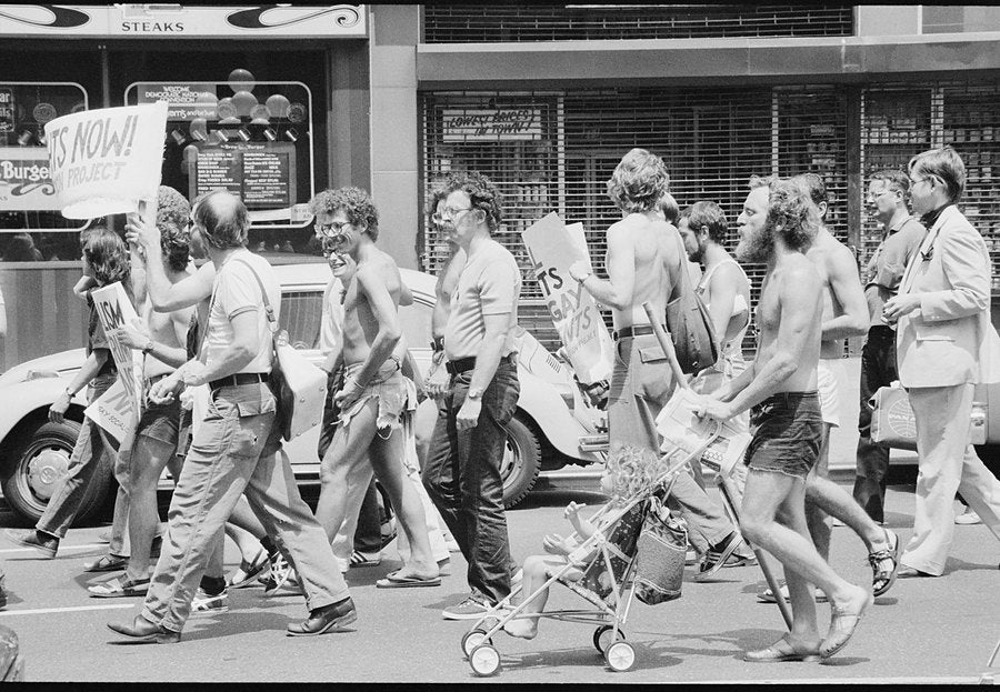 Marchers walk past a stroller on 34th Street at a gay rights demonstration, 1976.