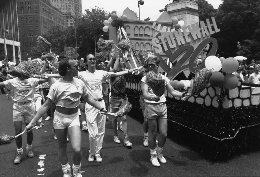 Dancers in white T-shirts wave pompoms beside the Stonewall 20 float, 1989.